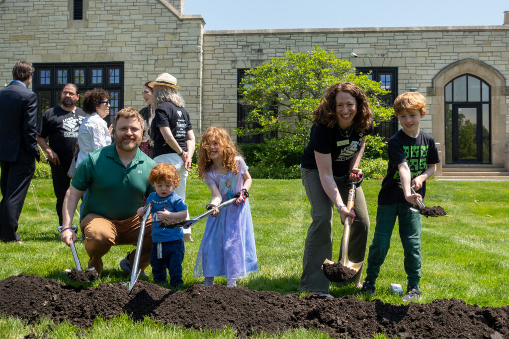 A family poses with shovels in the dirt for the groundbreaking