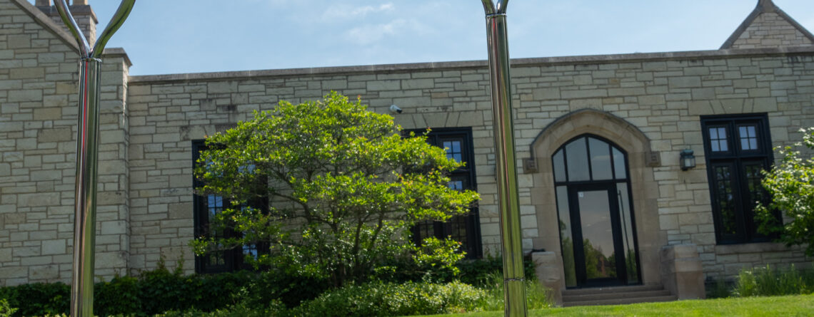 Two silver-handled shovels stand in a pile of dirt in front of the library's west side.