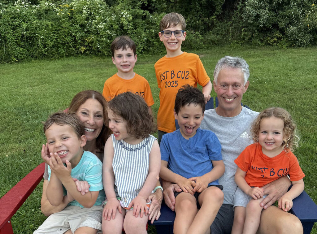 Family picture of Rob and  Terri Olian and their grandchildren on a bench, four children in their laps and two more children behind.