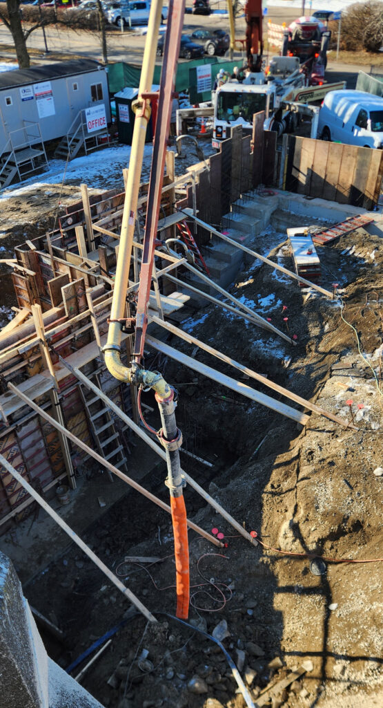 Concrete is fed into footing forms via a tube attached to a crane.